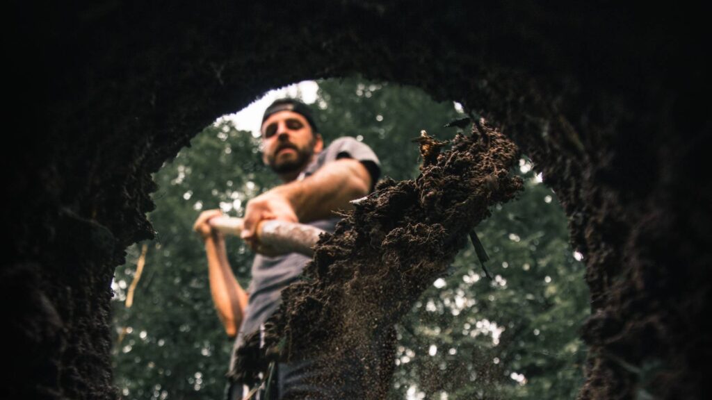 Man with shovel digging hole in the forest | Freshly Brewed Content